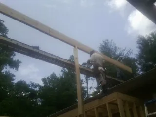 Carpenter setting a ridge beam over a new addition frame — Ice Dam Removal by Roofing Brothers in Revloc