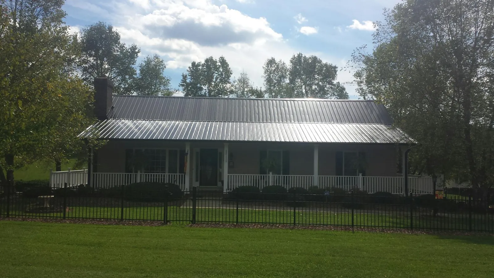Gray metal roof on a brick ranch with a full width front porch — Gutter Guard Installation work by our crew in Revloc