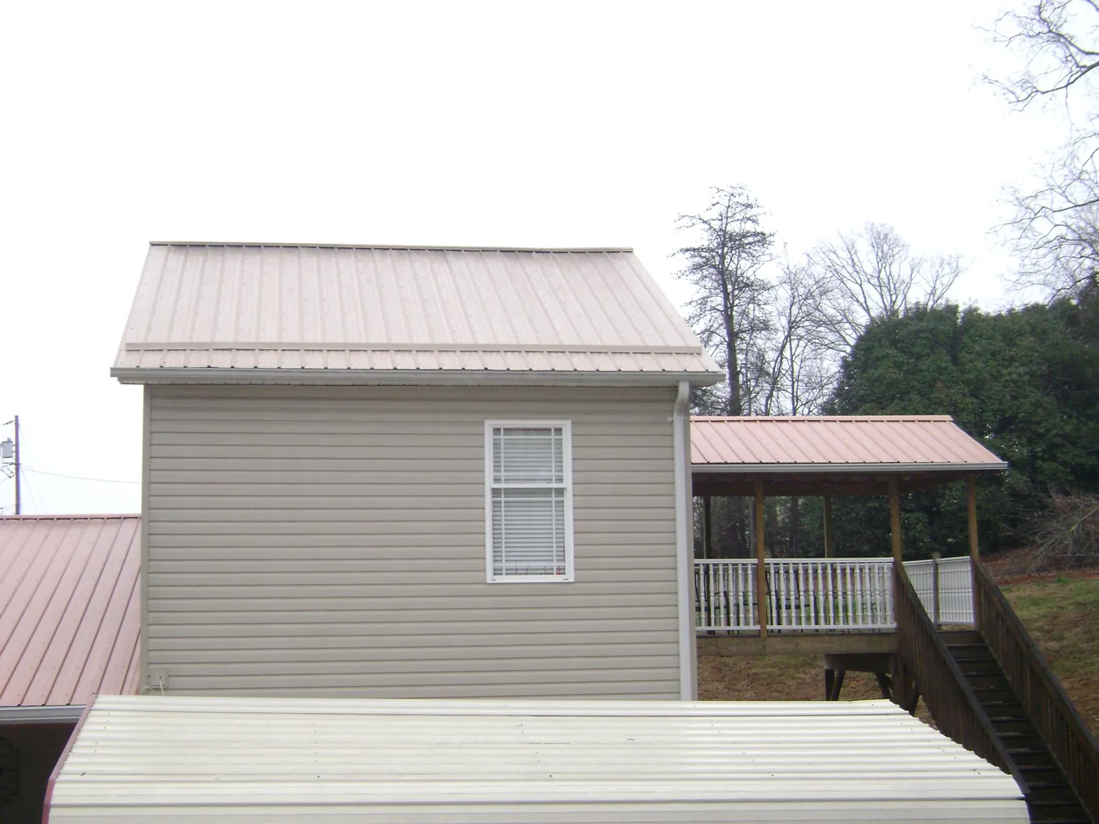 Tan metal roofs on a two story addition and attached porch, from a Roof Replacement job in Revloc