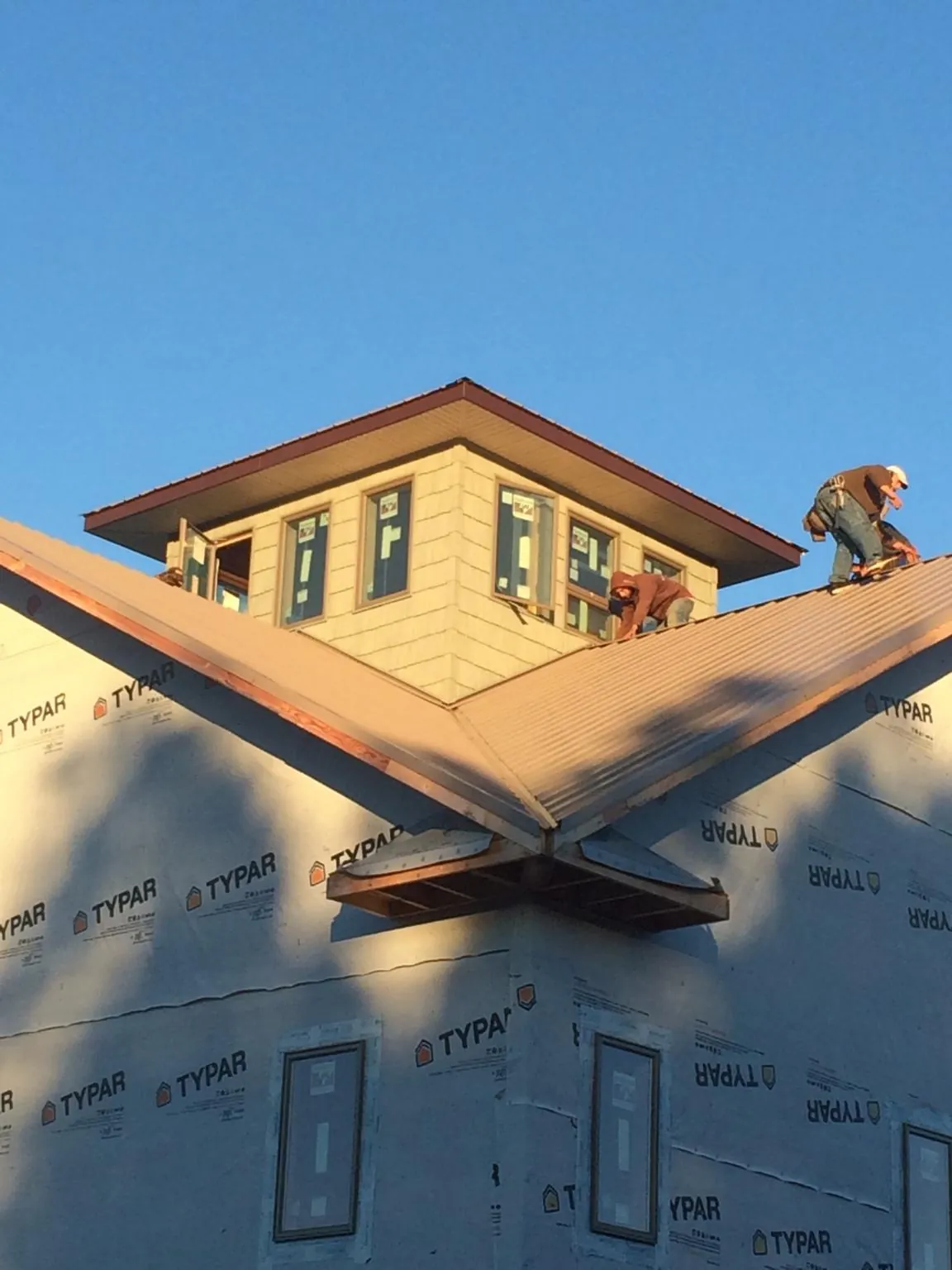 Roofers working around a rooftop cupola on a new metal roof at sunset — Roof Waterproofing in Revloc by Roofing Brothers